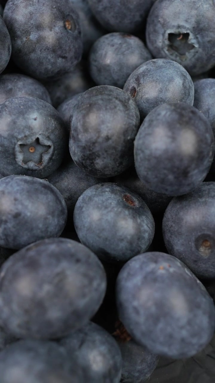 Mirtilli freschi e maturi riempiono l'inquadratura in un primo piano macro, creando un ricco sfondo di frutta per temi legati al cibo sano, alla nutrizione o al raccolto estivo.