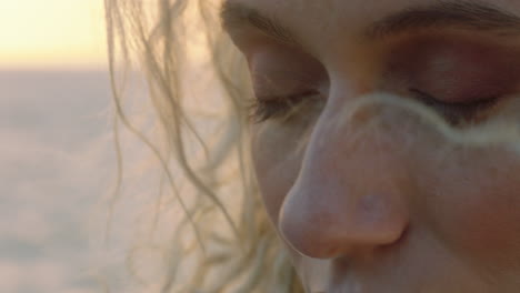 close up portrait of beautiful blonde woman enjoying peaceful seaside at sunset contemplating journey exploring spirituality feeling freedom with wind blowing hair