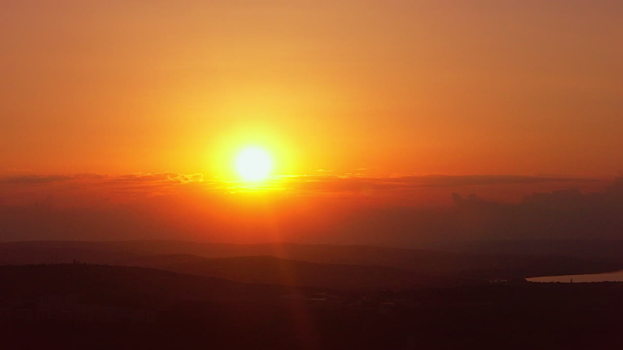 Aerial drone view of sunset. Hills, bright Sun, lake