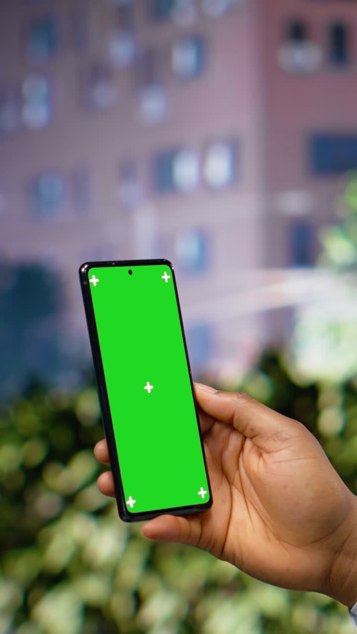 Vertical Video Vertical green screen phone held by black man on a busy city center street
