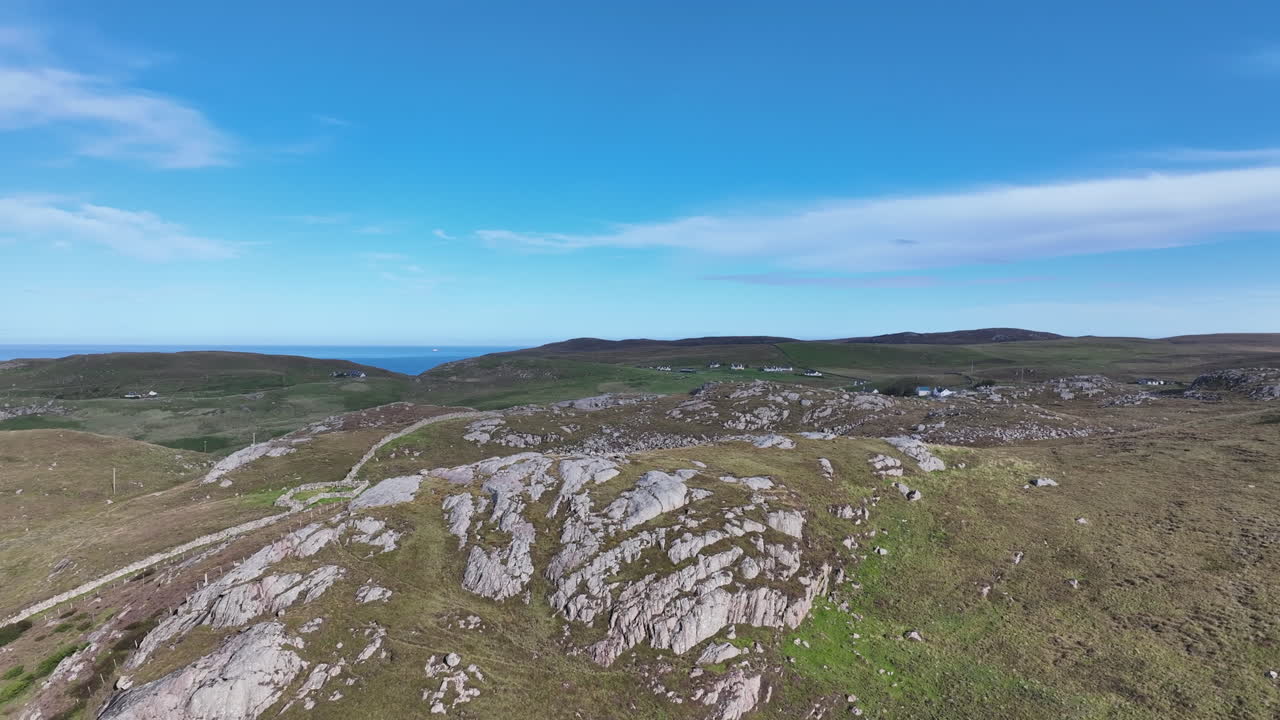Vista aerea delle Highlands scozzesi con colline rocciose, terreno verde e orizzonte marino in lontananza. Scattata con un drone in una giornata di sole, evidenziando la bellezza naturale e la natura selvaggia della Scozia