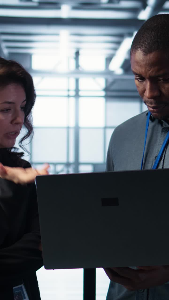 Vertical video Engineers using laptop in data center, managing server virtualization