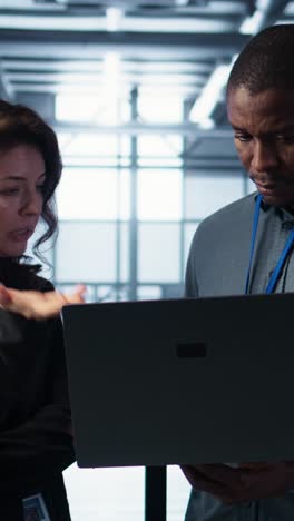 vertical video engineers using laptop in data center, managing server virtualization