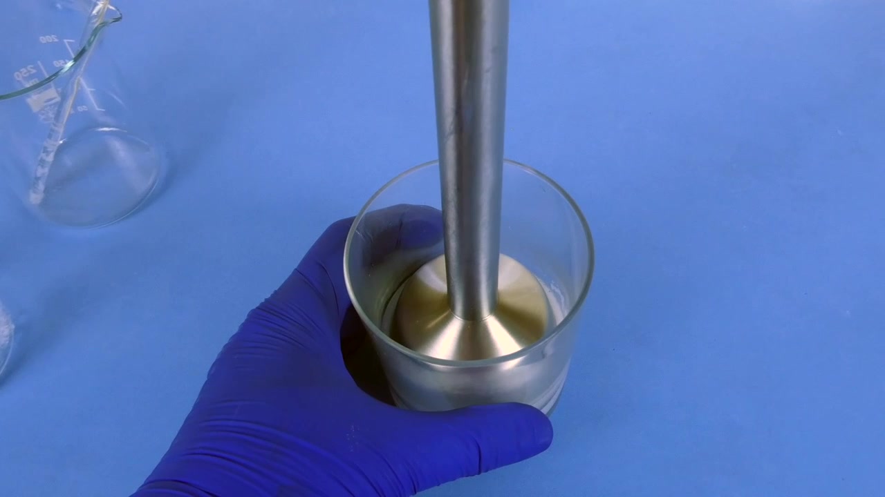 Farmaceut tilbereder en farmaceutisk emulsion i laboratoriet med en stavblender.