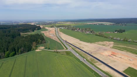 Aerial-view-of-road-under-construction-in-the-middle-of-green-fields