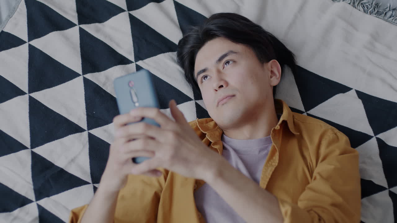 Man Lying Down on Bed, Using Smartphone