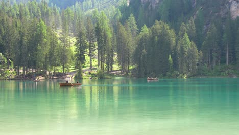 Gente-Remando-Y-Caminando-En-Un-Día-Soleado-En-El-Arbolado-Lago-Di-Braies,-Italia