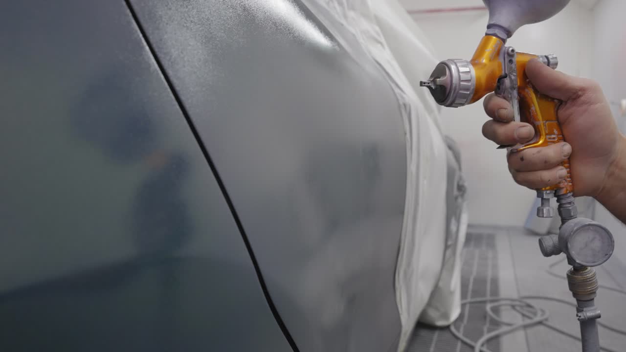 Close-up of painting a silver car with a professional air spray gun