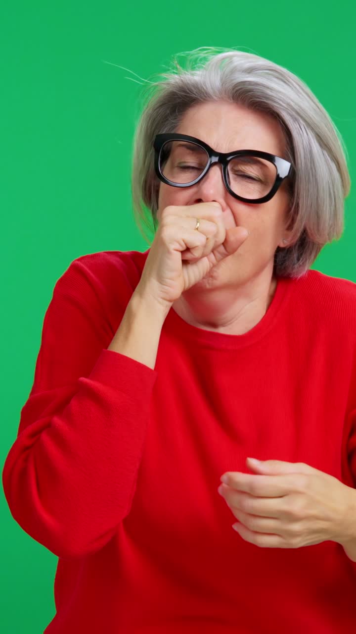 Donna matura che tossisce e mostra disagio su schermo verde