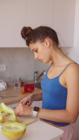 woman preparing melon and salad in kitchen