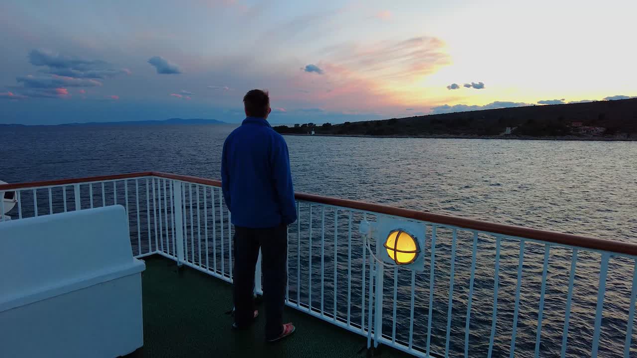 구름에서 거리를 바라보는 페리 보트의 부두 가장자리에 서 있는 남자의 패닝 백 뷰