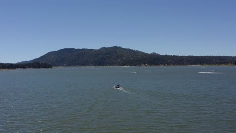 Aerial-drone-tracking-shot-of-a-boat-in-Big-Bear-Lake-in-San-Bernardino-County,-California