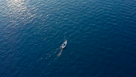 aerial top view of small sailboat moving in blue sea on a sunny day