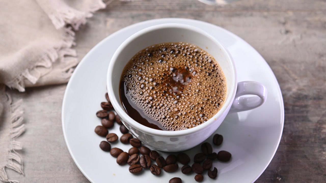 Hælder kaffe i en varm kop.