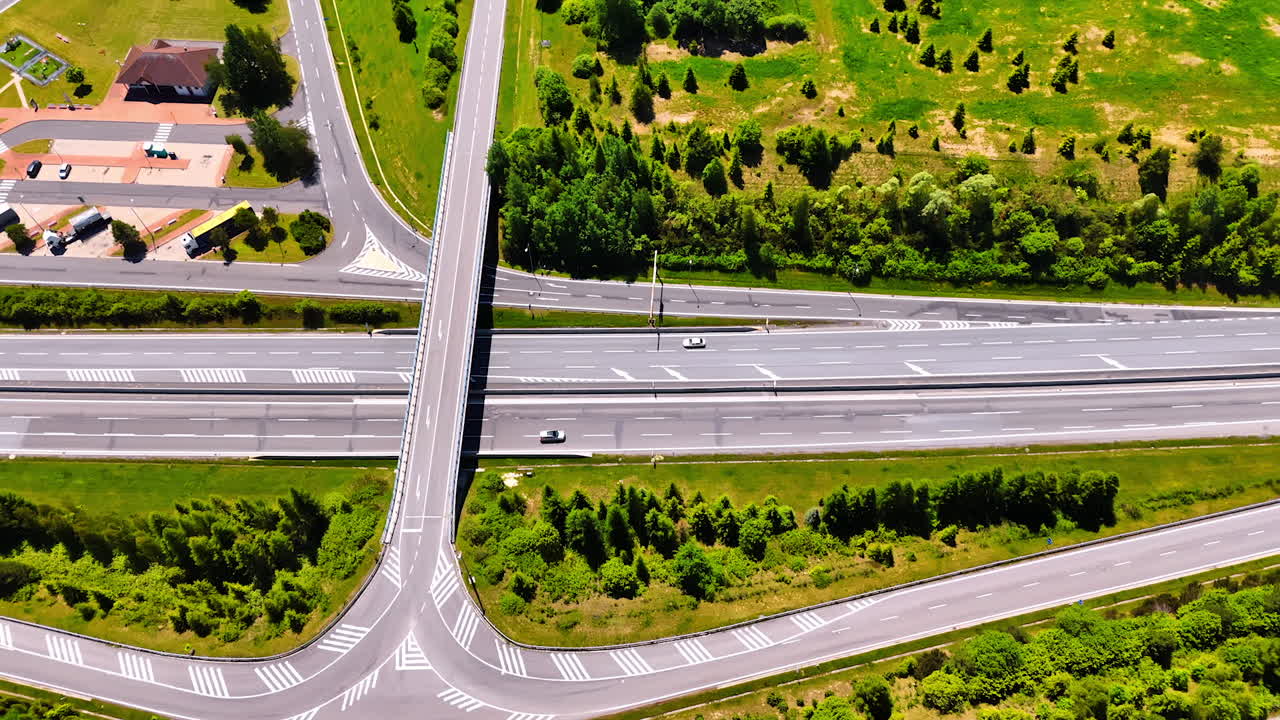 Highways and freeways surrounded by green lawns and trees. Road conjunction in Slovakia on sunny day. Top view