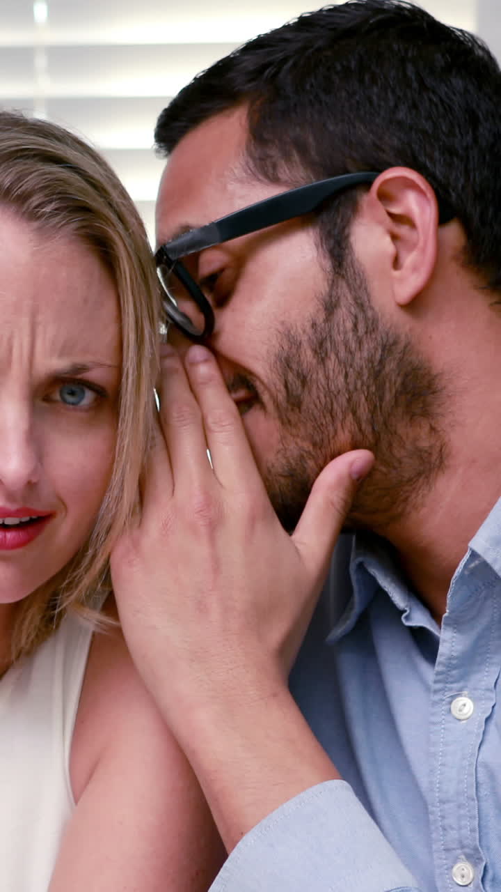 un hombre de negocios casual susurrando un secreto a un colega.