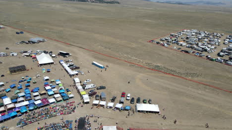 drone circling an outdoor music festival, people listening to music with food, and recreational vehicles and vans camped nearby