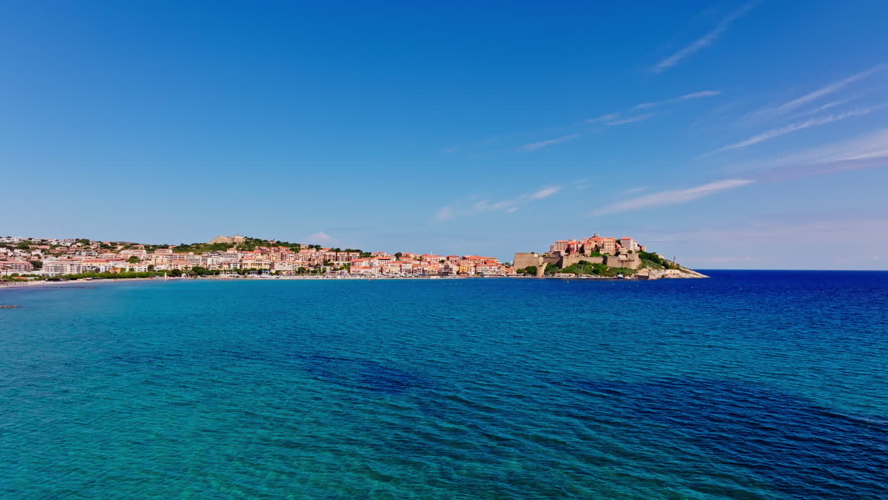 Ripresa aerea con drone della città costiera di Calvi, in Corsica. Vista della cittadella che domina la città. Destinazione per le vacanze estive. Cielo azzurro brillante, mare turchese vivace.