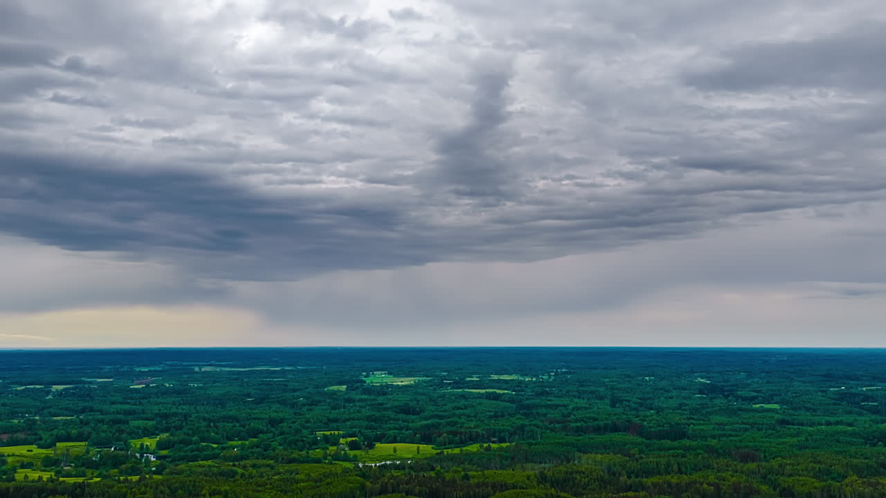 Time lapse of dark storm clouds moving over green farmland landscape, natural backdrop of storm grey clouds