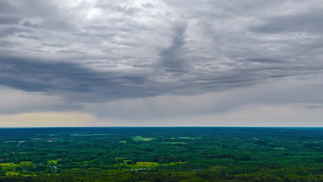 time lapse of dark storm clouds moving over green farmland landscape, natural backdrop of storm grey clouds