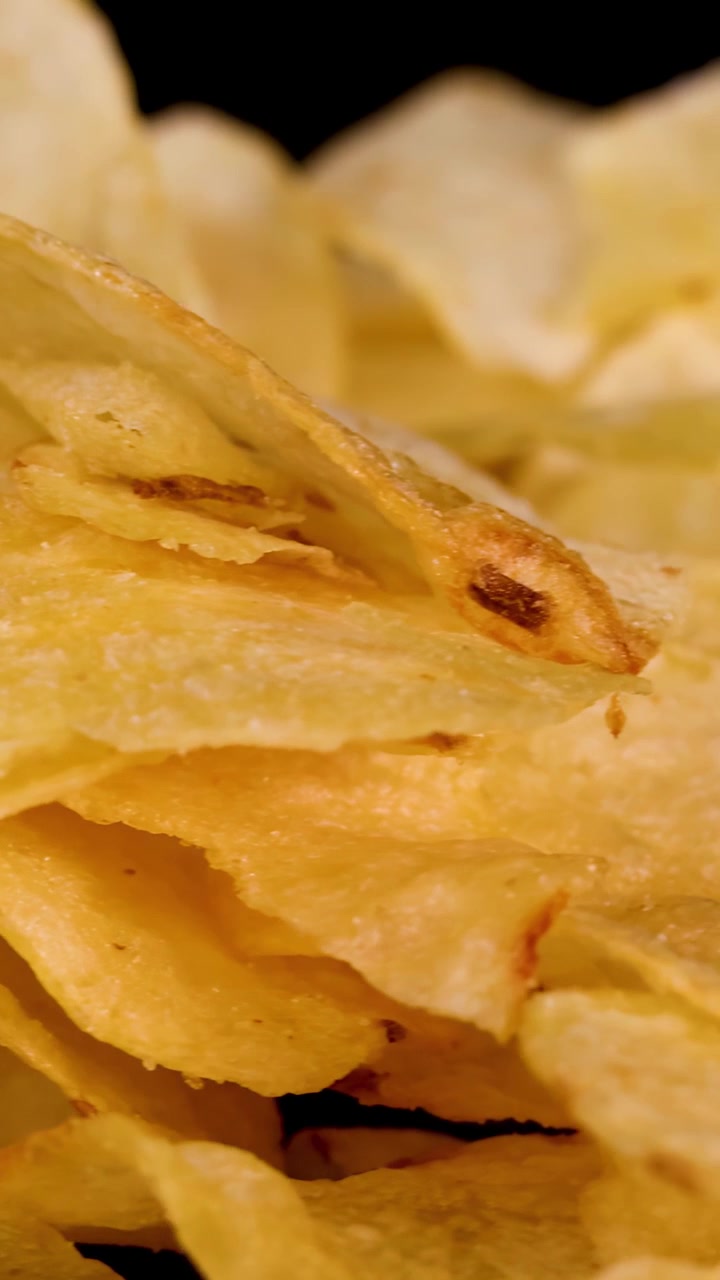 Patatine fritte croccanti ruotano in primo piano sotto l'illuminazione da studio, enfatizzando la consistenza e il colore dorato.