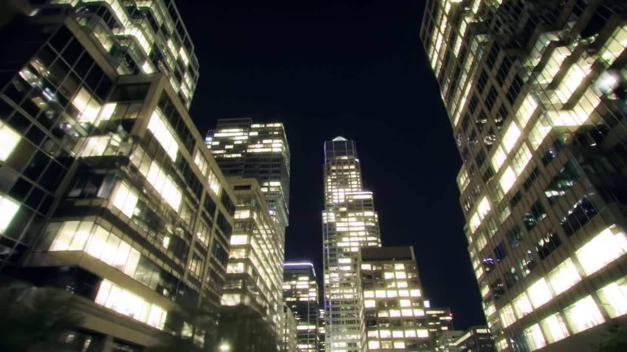 A Stunning Nighttime Urban Scene Captured from Between Skyscrapers, Showcasing Brightly Lit Windows Against a Deep Blue Sky, Creating a Majestic Cityscape Atmosphere