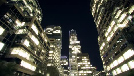 a stunning nighttime urban scene captured from between skyscrapers, showcasing brightly lit windows against a deep blue sky, creating a majestic cityscape atmosphere