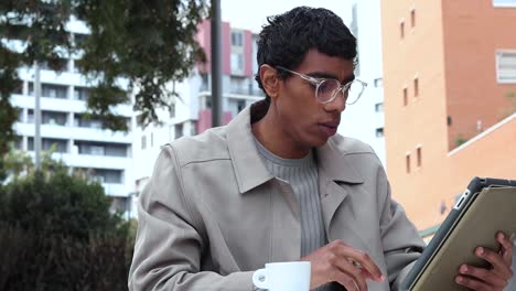 Focused-black-man-using-tablet-and-drinking-coffee