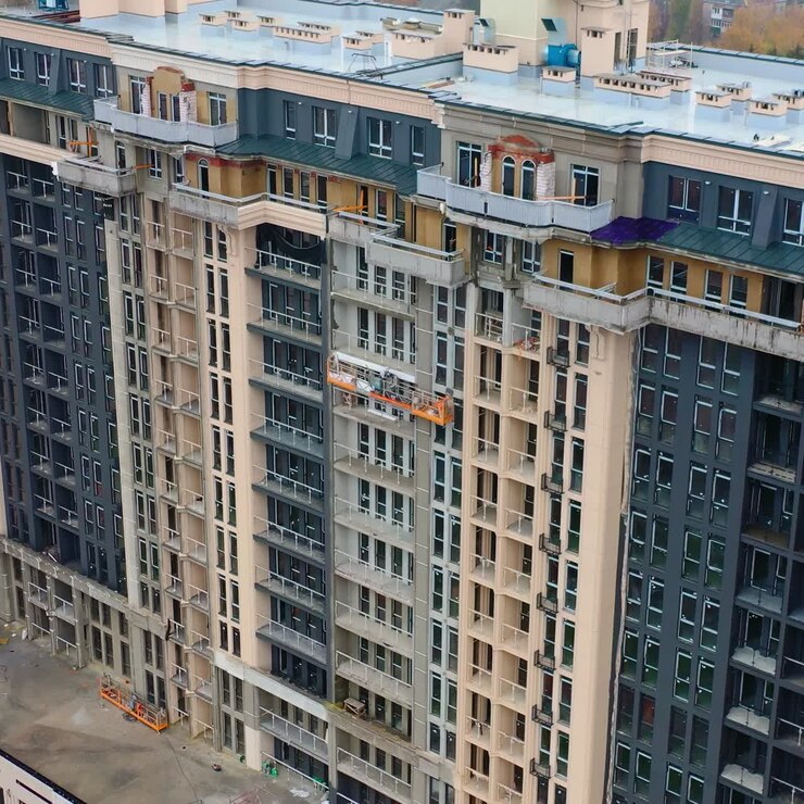 Construction of a tall building in the city. Modern block of flats builds in the city. New tower architecture with windows. Aerial view.