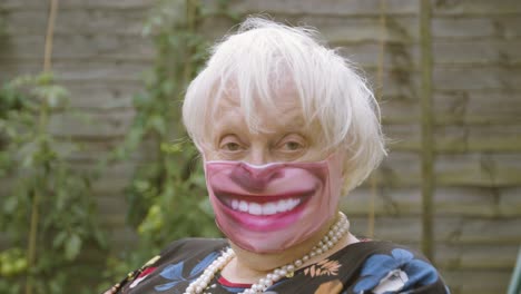 elderly woman wearing a smiley face face mask looking at the camera close up