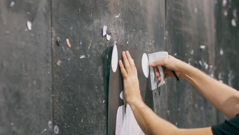 Close-up on the hands of a man stapling a firing range target to a wall