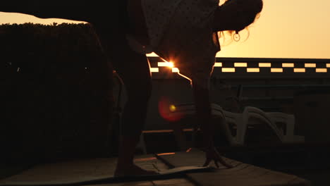 reflection in the water of young woman do yoga pose at sunrise with a strong sun backlight