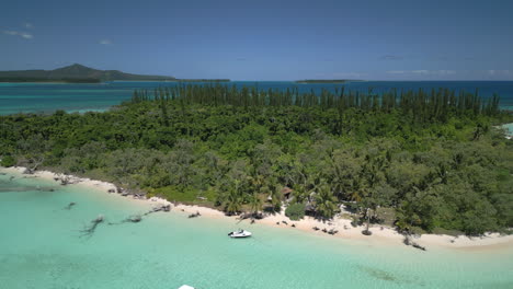 boats bring tourists to the pristine beach on ilot moro in the isle of pines - pull back aerial reveal