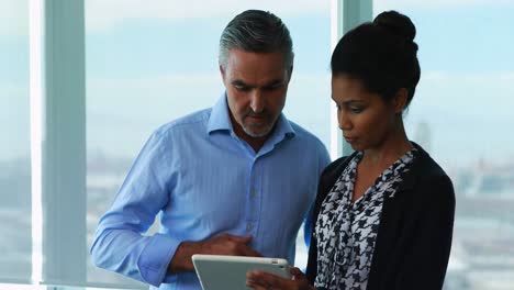 Executives-discussing-over-digital-tablet-in-office