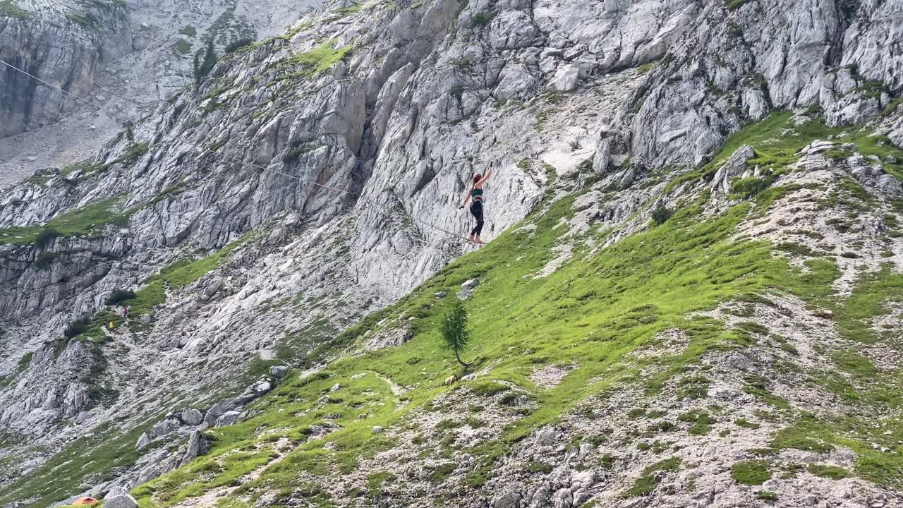 Woman on Slack line in the Italian Alps. Mountain Goat in the background.