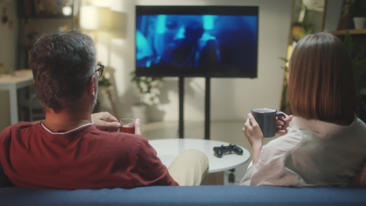 Couple relaxing at home watching TV or playing video games