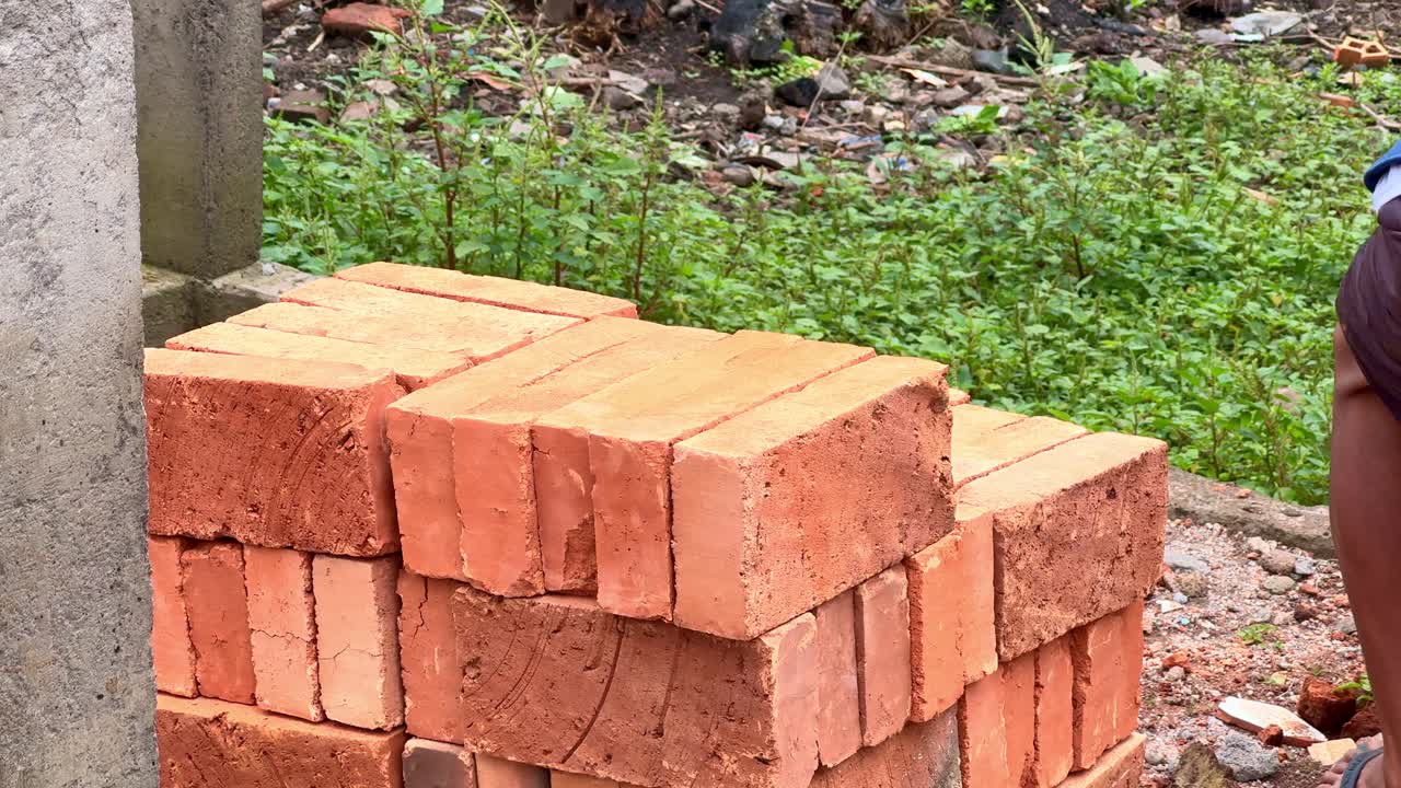 Close up of a worker arranging red clay bricks by hand at a construction site. Manual building material preparation