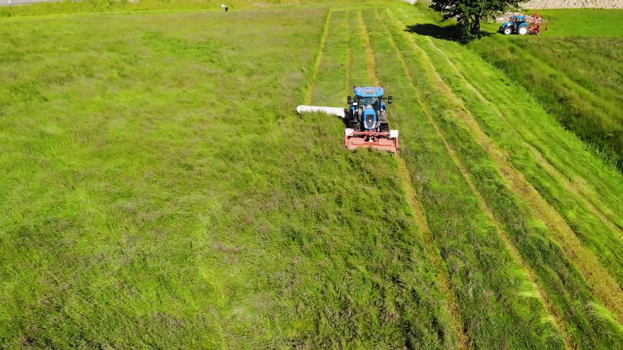 Tractor with double mower filmed during hay harvest