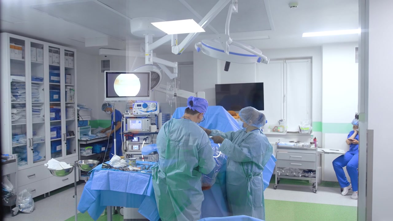 Surgery room with the procedure taking place. Footage through the window in the door to the operational room.