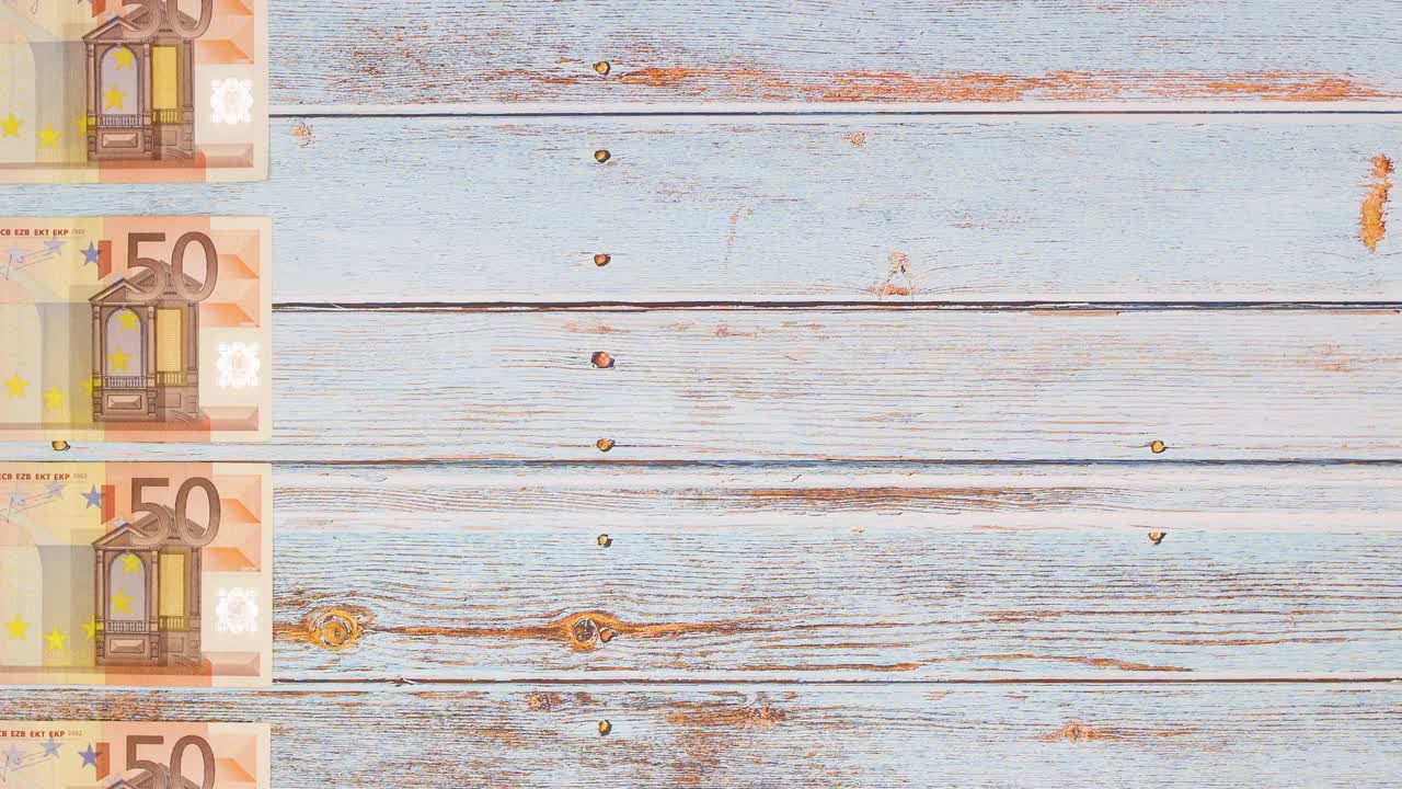 billetes de cincuenta euros que pasan por el lado izquierdo de la mesa de madera - stop motion