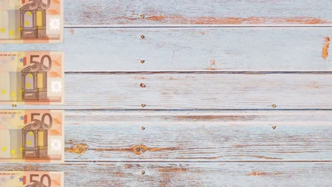 banknotes of fifty euros passing on left side of wooden table - stop motion