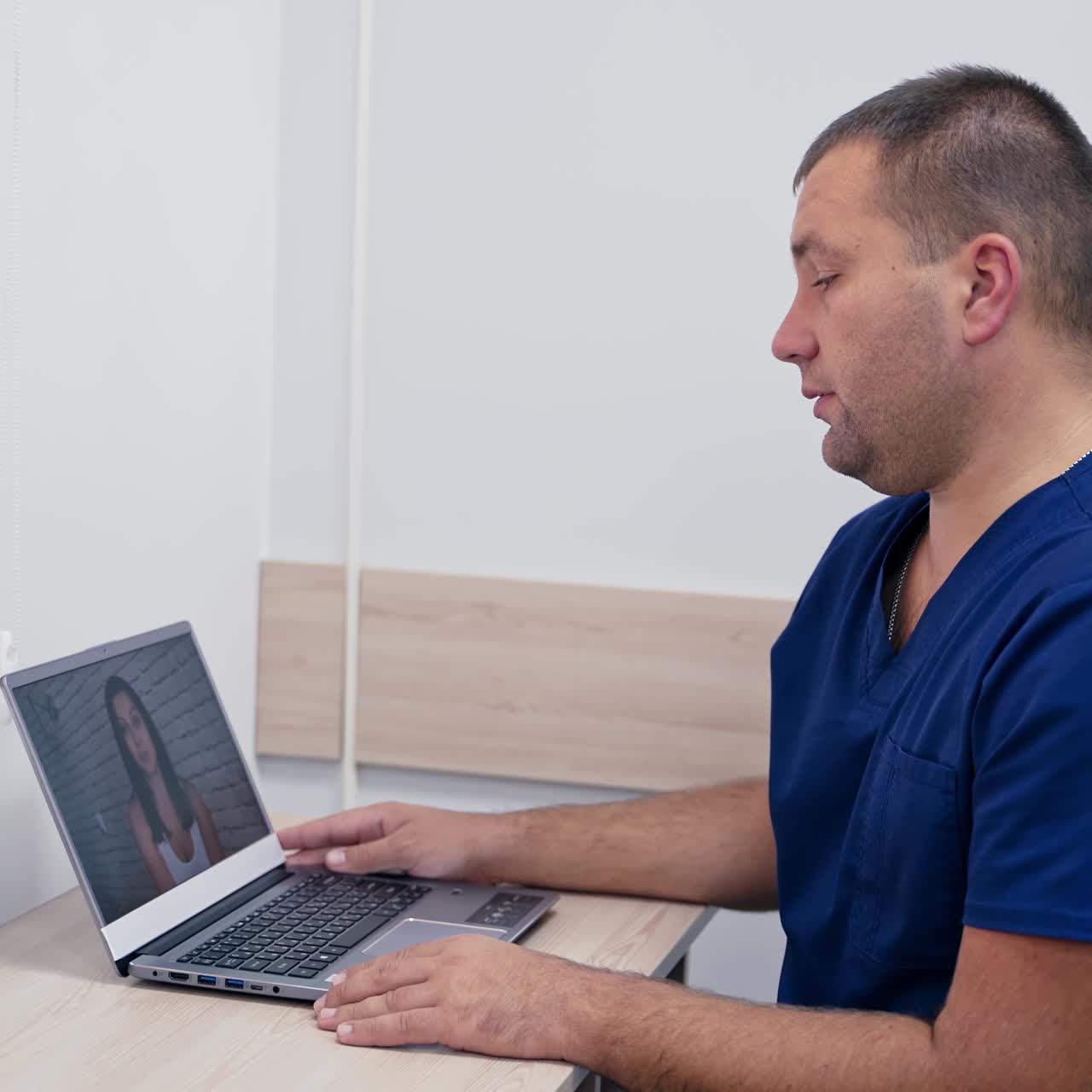 Medical specialist giving online consultation. Professional doctor sitting at desk and looking on pc screen while talking to a patient about health problems.