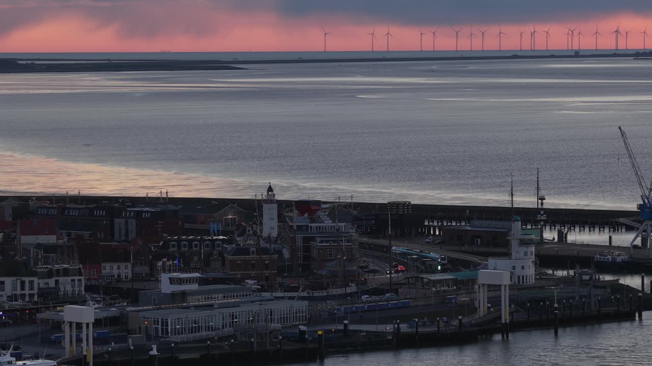 Aerial drone video of the industrial sea port of Harlingen, Friesland, at dusk on the Wadden Sea, showcasing a mix of seagoing vessels, ferries, Brown Fleet historic ships, and official service boats