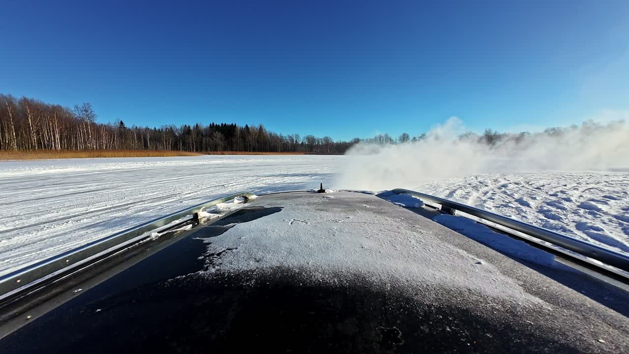 Dachmontierte Rückansicht eines Autos, das mit driftender Bewegung und Schneefahne durch den Schnee gleitet.