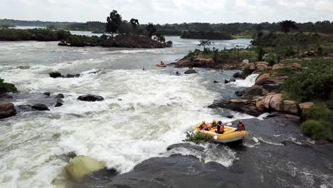 Drone-view-of-a-yellow-boat-white-water-rafting-down-the-falls-of-the-Nile-River-in-Jinja,-Uganda
