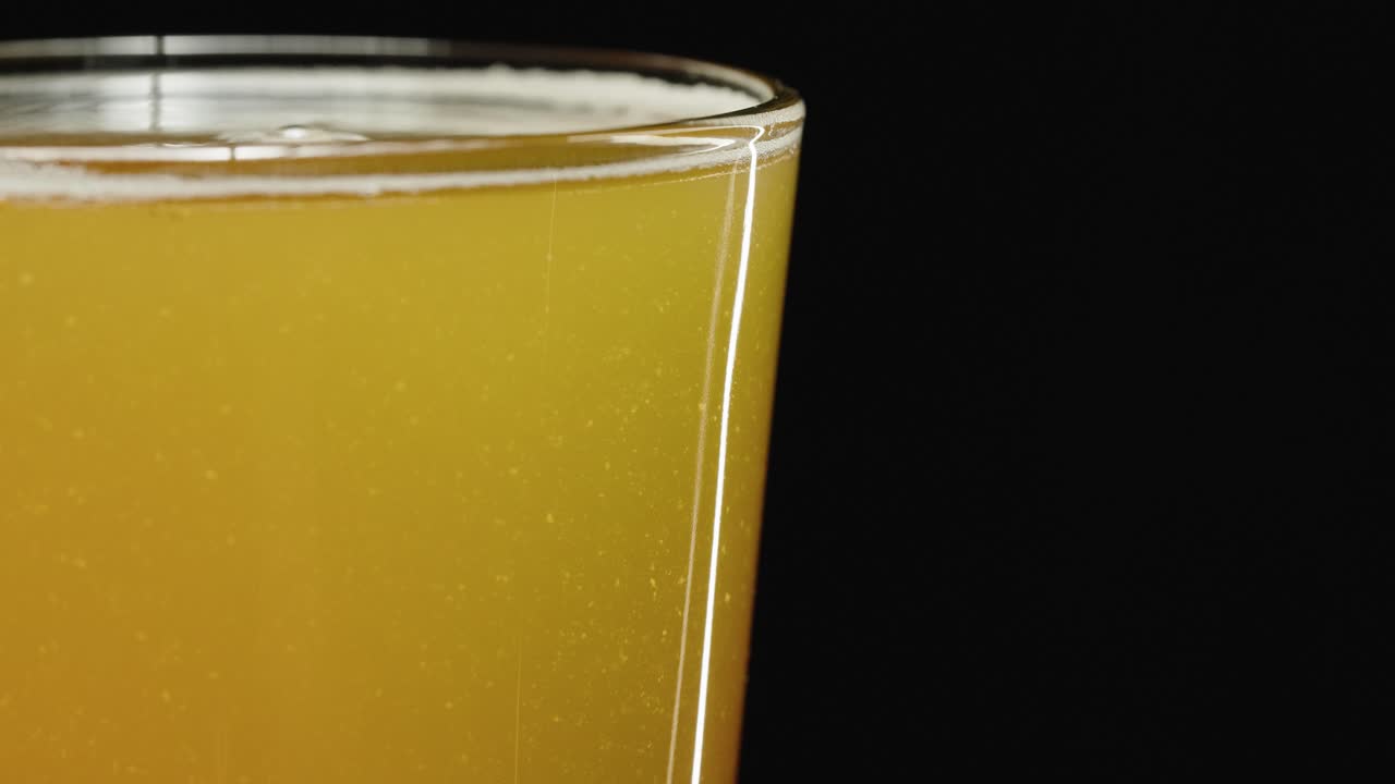 cerveza en un vaso frío que muestra el sedimento en una cerveza artesanal ipa nebulosa, fondo negro de vista lateral