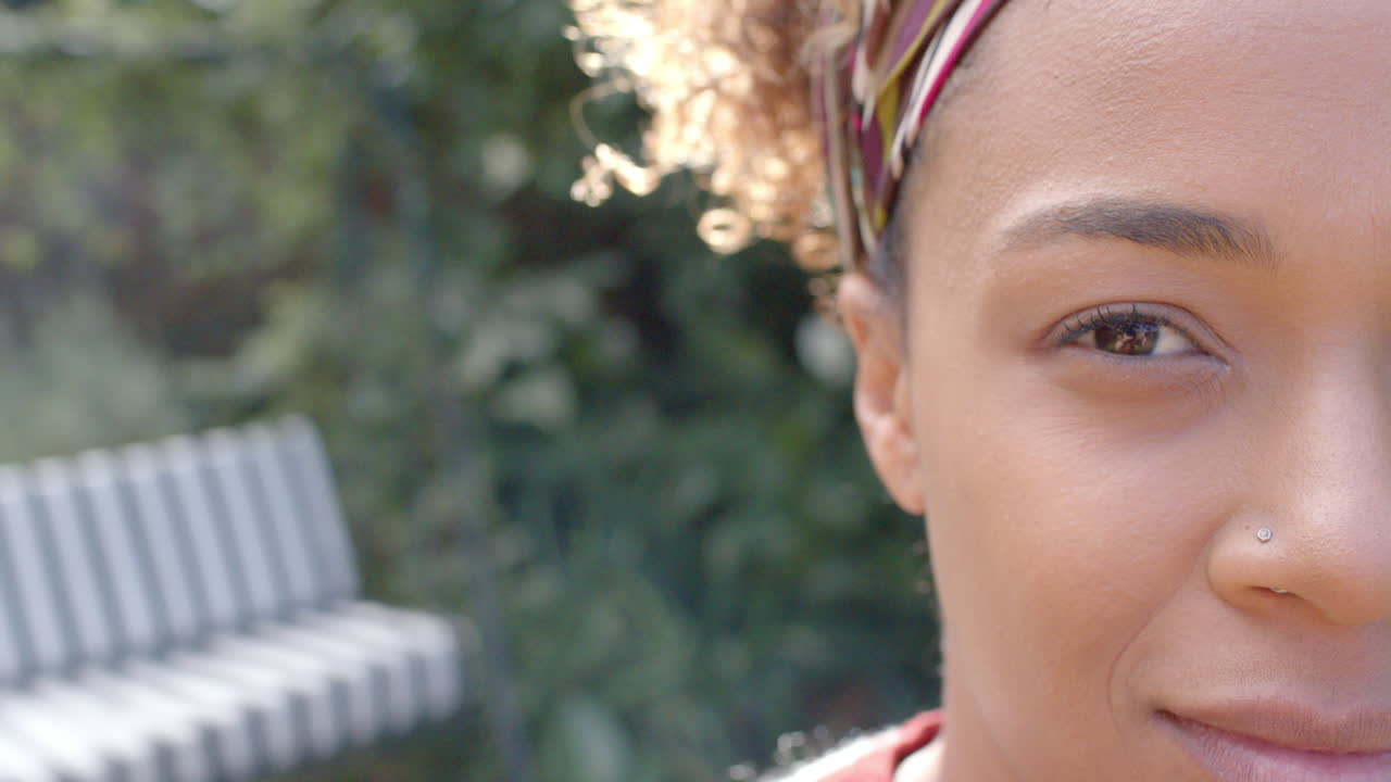 retrato de una feliz mujer afroamericana sonriendo en el jardín, espacio de copia, cámara lenta