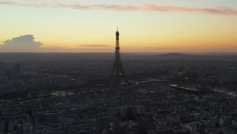 Descending-footage-of-city-at-dusk.-Beautiful-view-of-silhouette-of-historic-structure-of-Eiffel-Tower-against-sunset-sky.-Paris,-France