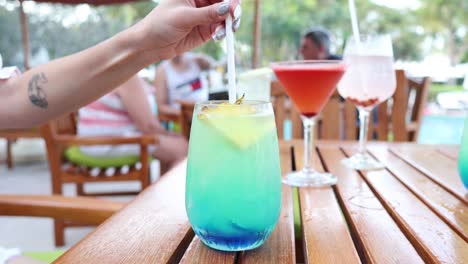 person stirring a layered blue cocktail outdoors