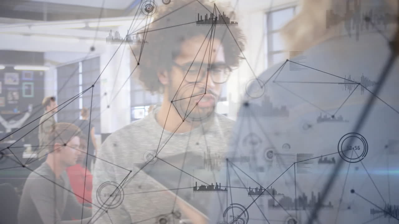 Two professionals leaning over computer in business office, displaying network diagrams and charts